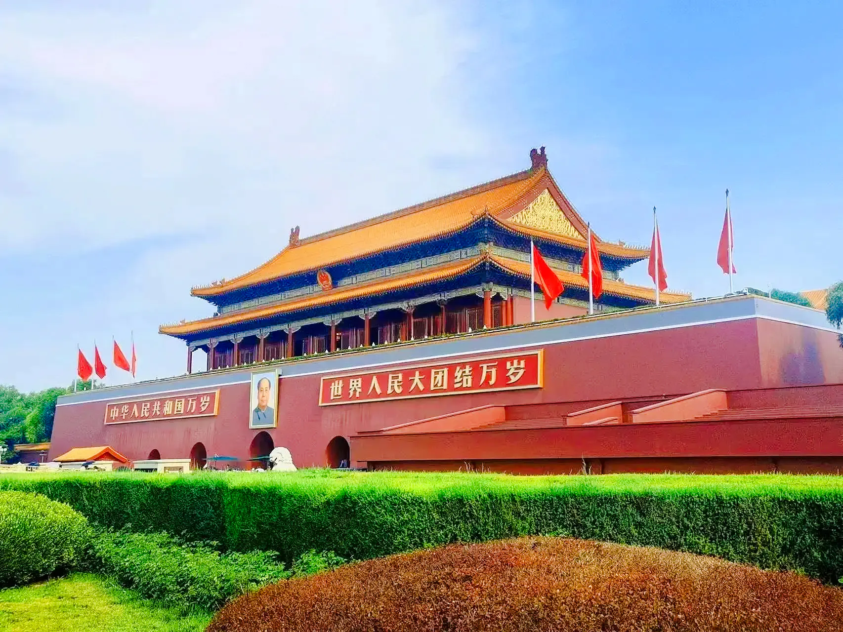 Tiananmen Gate in Beijing, China, with red flags and Mao Zedong portrait.