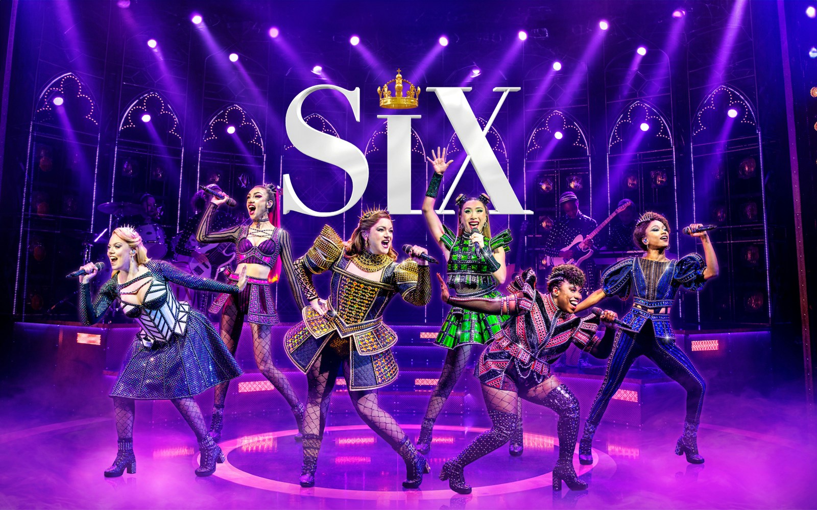 Performers on stage in vibrant costumes during the musical "Six" with dramatic lighting.