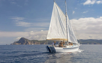 Tourists enjoying a private sunset cruise on a classic sailboat in Ibiza.