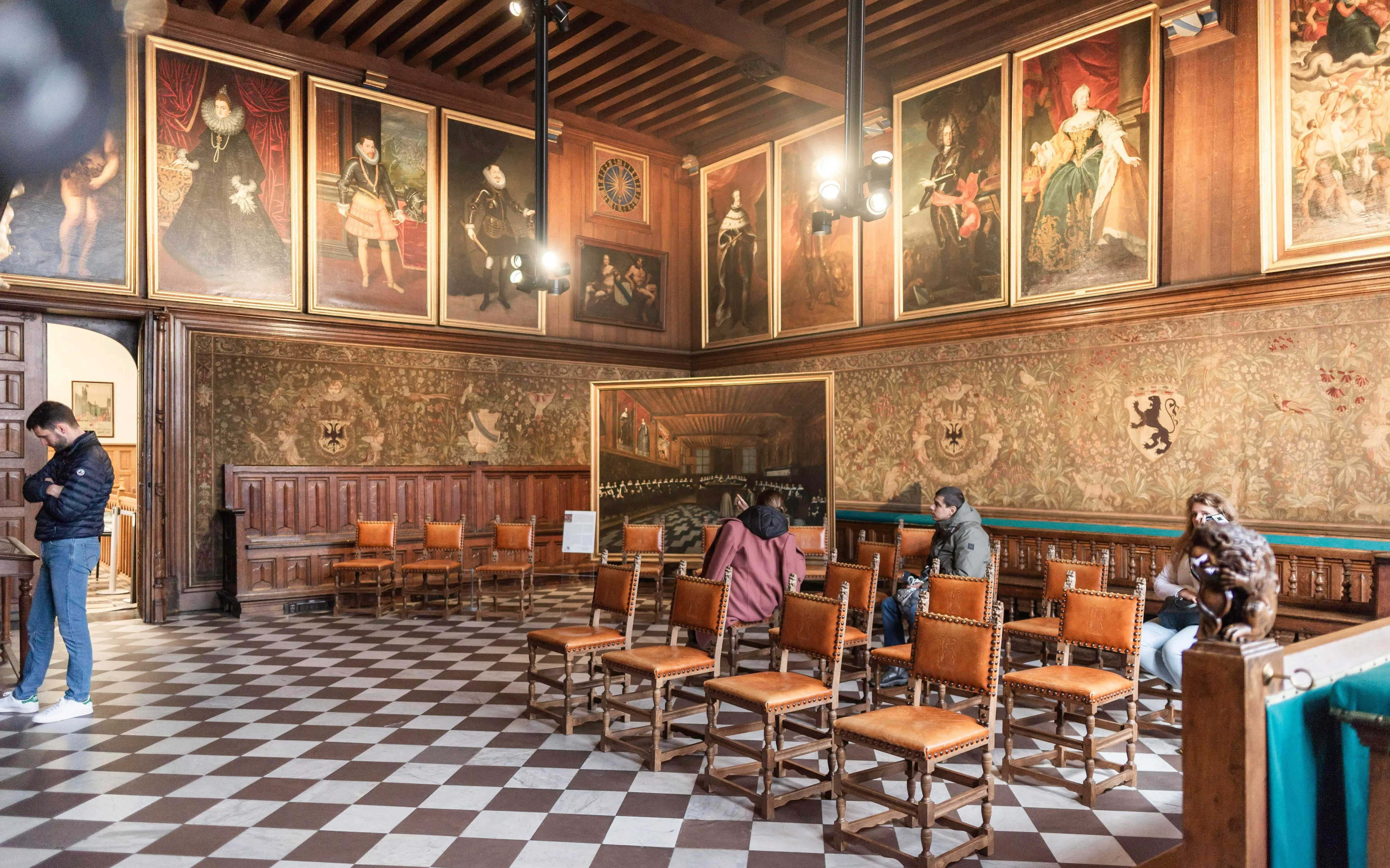 Brugse Vrije interior with historical paintings and visitors in Bruges, Belgium.