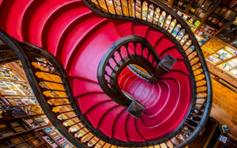 Curved red staircase inside Livraria Lello, Porto.