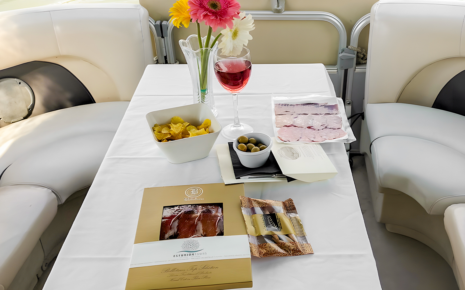 Tapas and drink setup on Guadalquivir River cruise table with olives, chips, and wine.