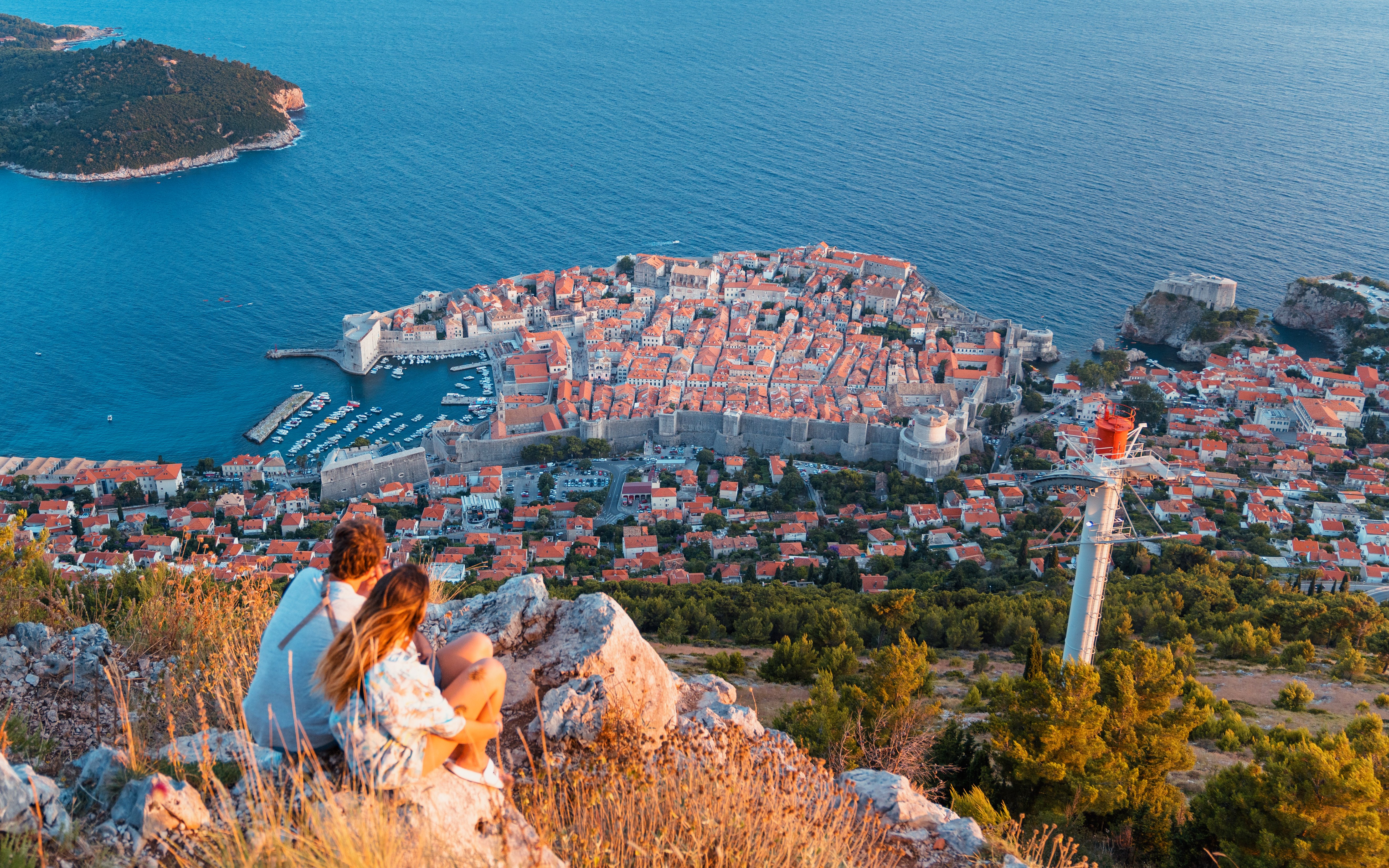 Young couple overlooking Dubrovnik from Fort Imperial, Croatia, with city walls and Adriatic Sea.