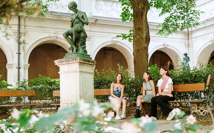 Visitors sitting near a statue in the courtyard of the Museum of Fine Arts, Lyon, France.