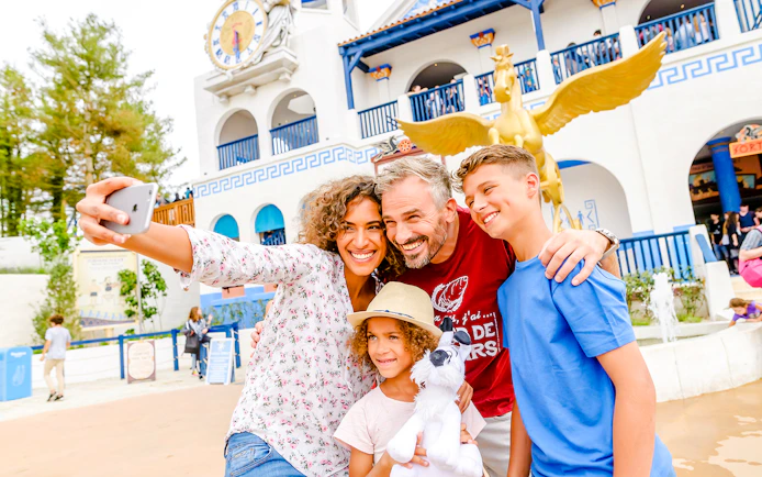 Family taking a selfie at Parc Asterix with Pegasus statue in the background.