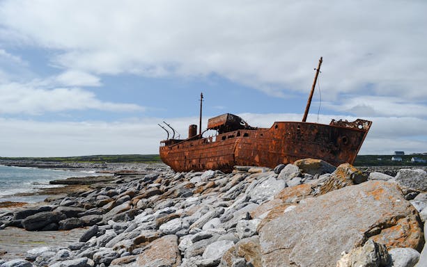 Rusty MV Plassy shipwreck on rocky shore, Inisheer Island, Ireland.