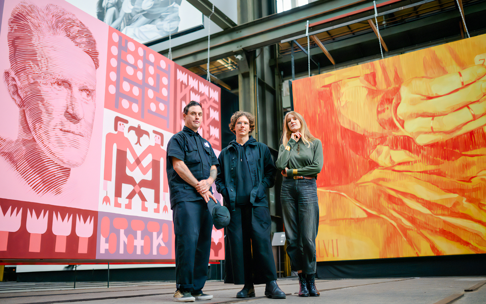 Artists at Straat Museum with large colorful murals in the background.