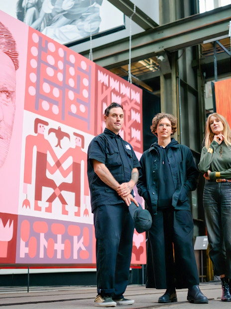 Artists at Straat Museum with large colorful murals in the background.