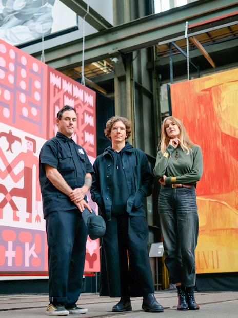 Artists at Straat Museum with large colorful murals in the background.