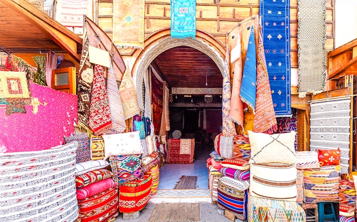 Colorful textiles and rugs displayed at a shop in the Medina Souks, Marrakesh.