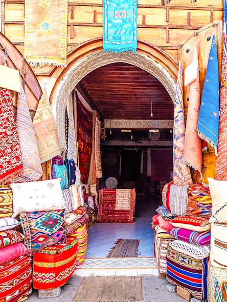 Colorful textiles and rugs displayed at a shop in the Medina Souks, Marrakesh.