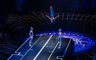 Acrobat flipping mid-air during La Perle performance at Tower Bridge.
