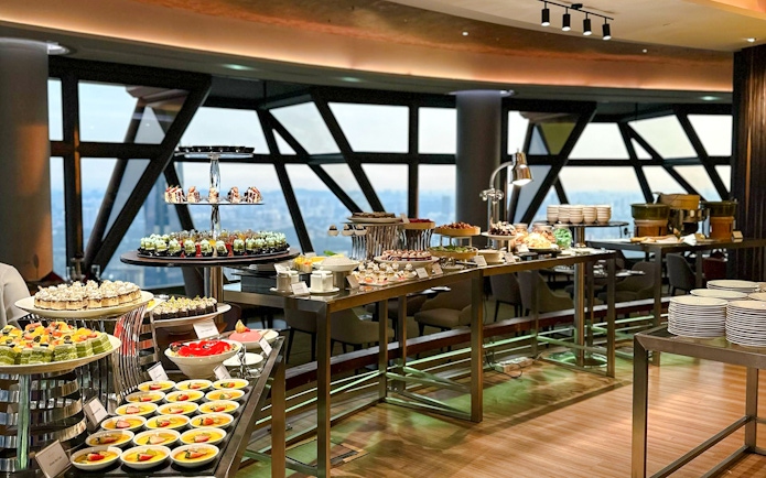 Buffet spread at ORBIT Revolving Restaurant in KL Tower with city view.