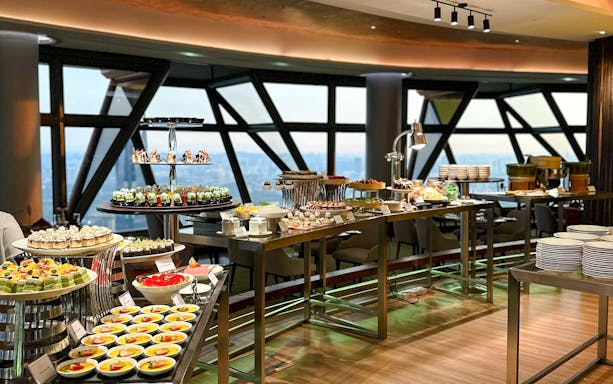 Buffet spread at ORBIT Revolving Restaurant in KL Tower with city view.