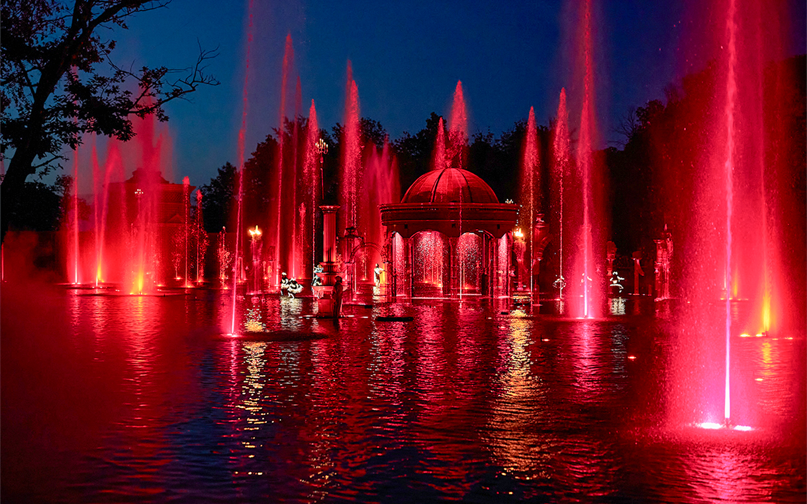 Fountain show at night with red lights at Puy du Fou Theme Park.