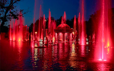 Fountain show at night with red lights at Puy du Fou Theme Park.