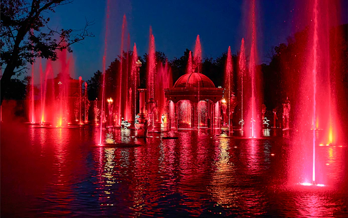 Fountain show at night with red lights at Puy du Fou Theme Park.