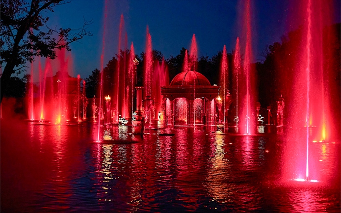 Fountain show at night with red lights at Puy du Fou Theme Park.