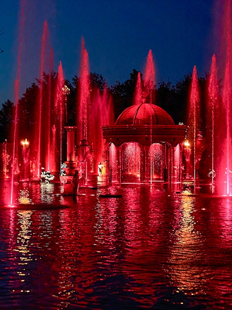 Fountain show at night with red lights at Puy du Fou Theme Park.