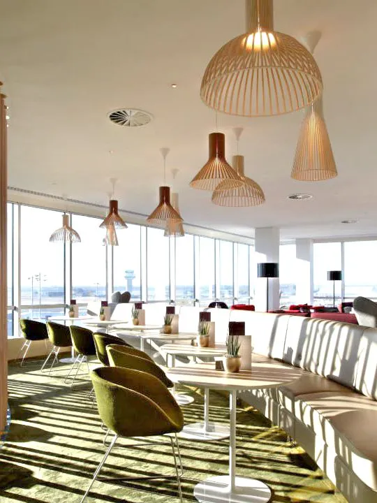 Plaza Premium Lounge seating area with tables and chairs, North Terminal, London Gatwick Airport.