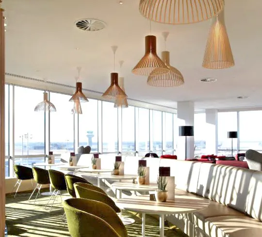 Plaza Premium Lounge seating area with tables and chairs, North Terminal, London Gatwick Airport.