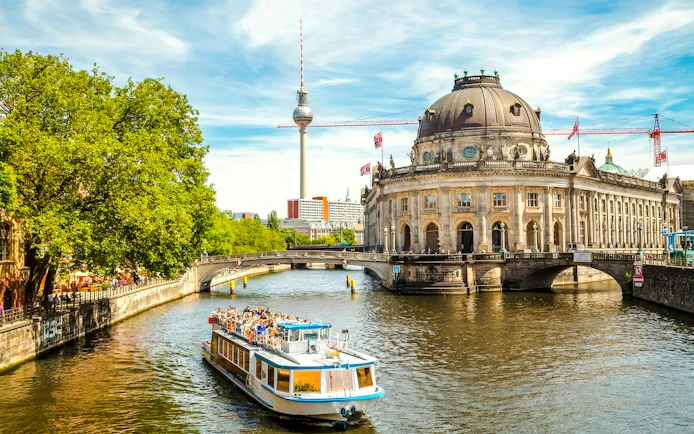 Boat on the Spree River near Berlin Cathedral and TV Tower during hop-on hop-off tour.