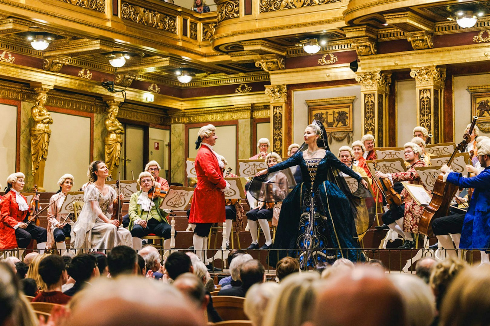 Mozart Orchestra performing in Vienna's Golden Hall with musicians in period costumes.