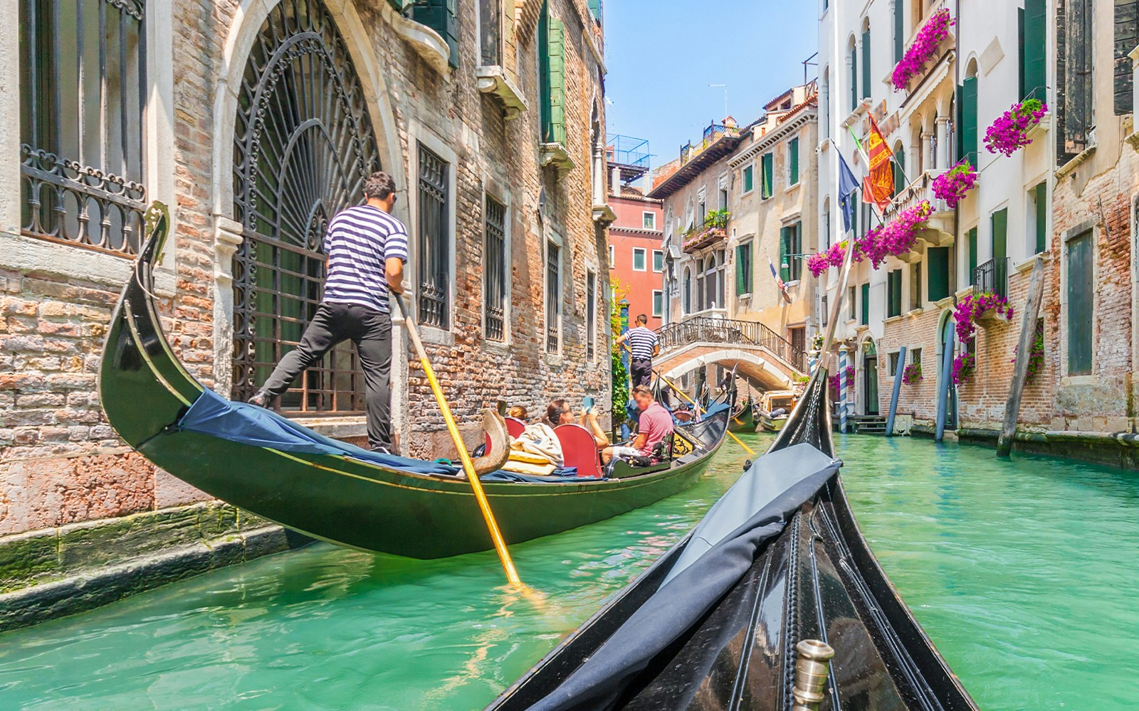 Gondola ride through Venice canal with vibrant buildings and flowers.