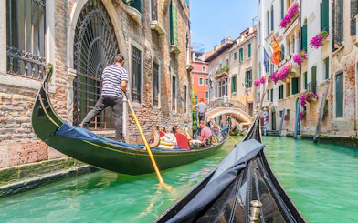 Gondola ride through Venice canal with vibrant buildings and flowers.