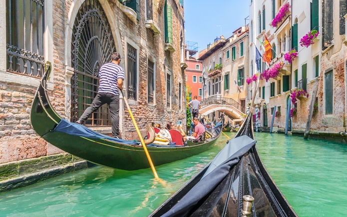 Gondola ride through Venice canal with vibrant buildings and flowers.