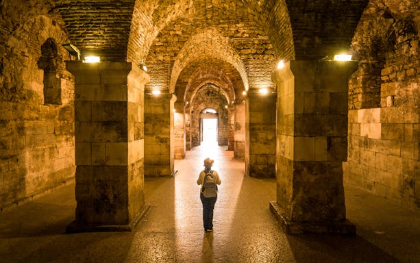 Visitor exploring the ancient cellars of Diocletian's Palace in Split, Croatia.