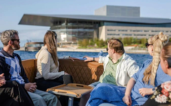 Guests on a guided boat tour in Copenhagen with the Opera House in view.