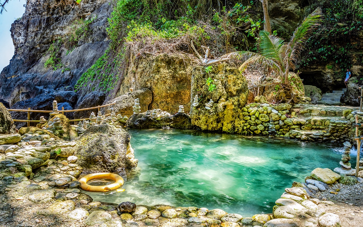 Tembeling Beach cave pool with turquoise water and stone formations in Bali.