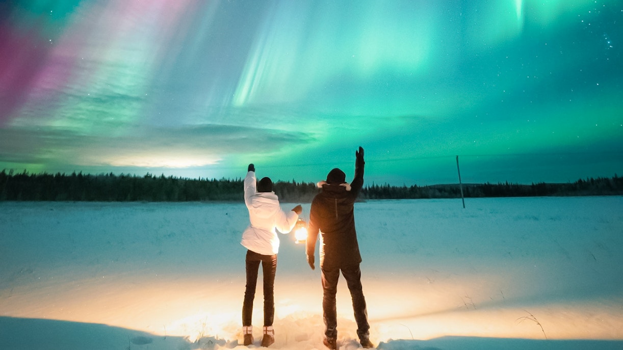 Couple watching Northern Lights in Levi, Finland.