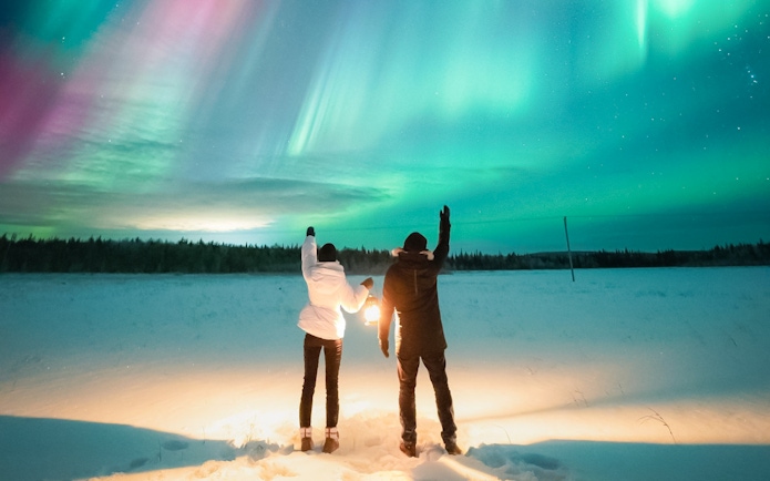 Couple watching Northern Lights in Levi, Finland.