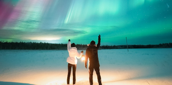Couple watching Northern Lights in Levi, Finland.