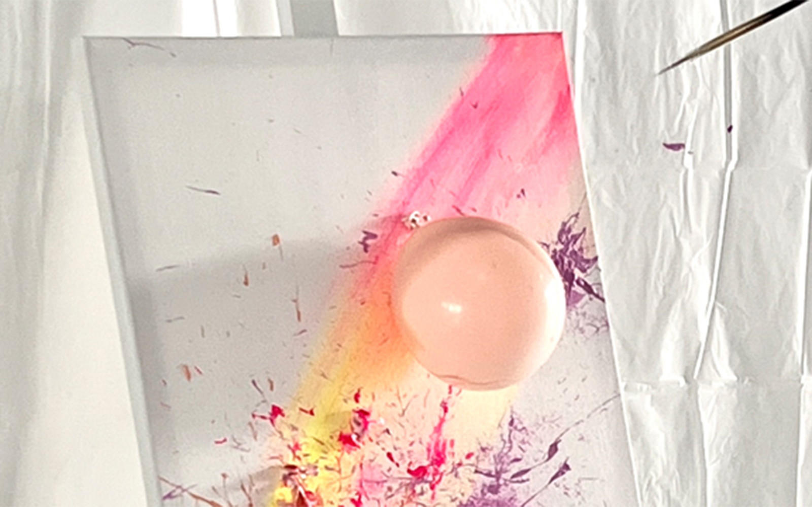 Balloon splatter art on canvas with vibrant paint streaks at workshop.