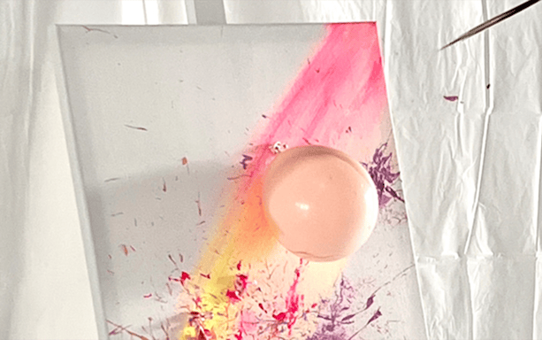 Balloon splatter art on canvas with vibrant paint streaks at workshop.