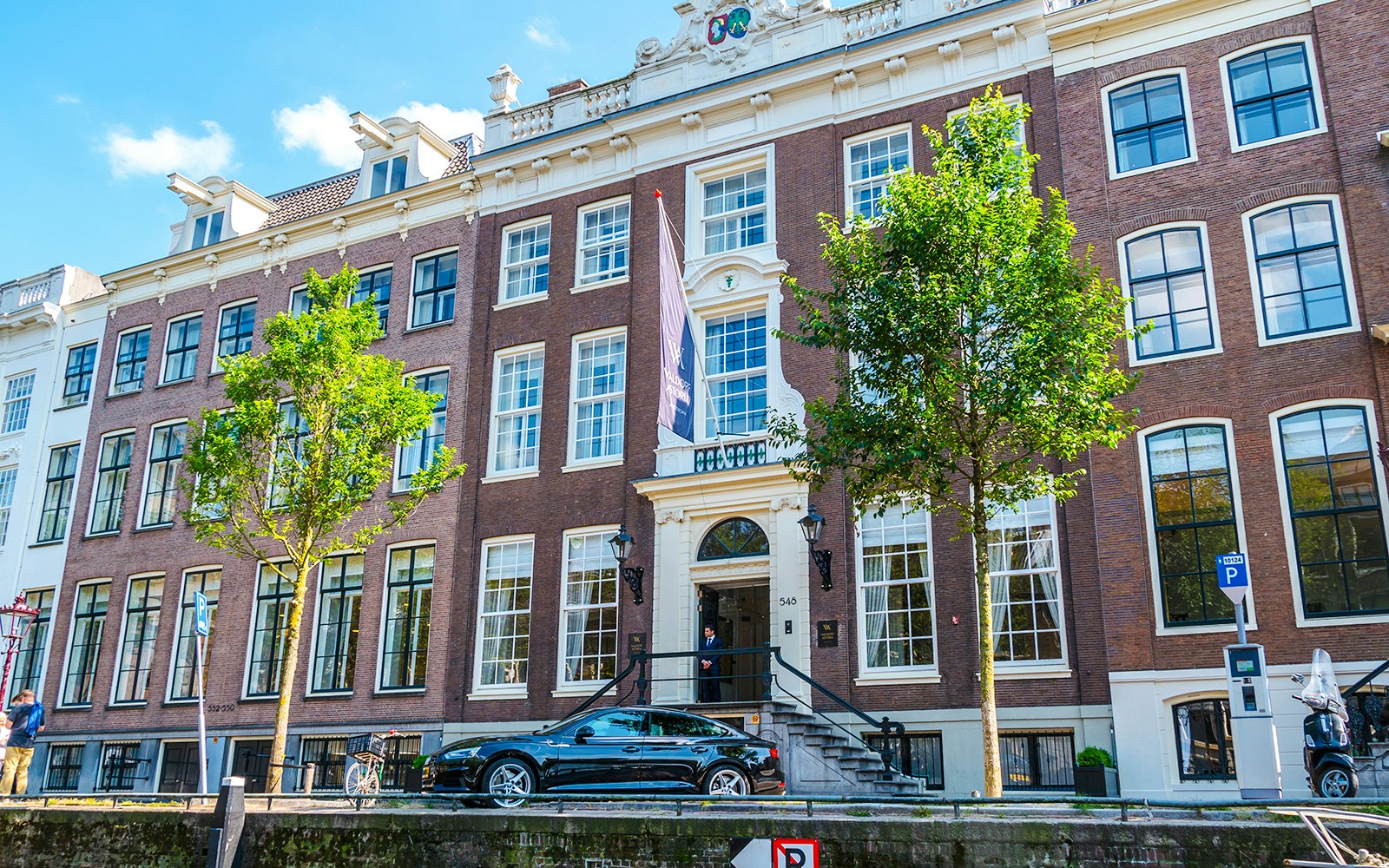 Waldorf Astoria Amsterdam facade with canal view and parked car.