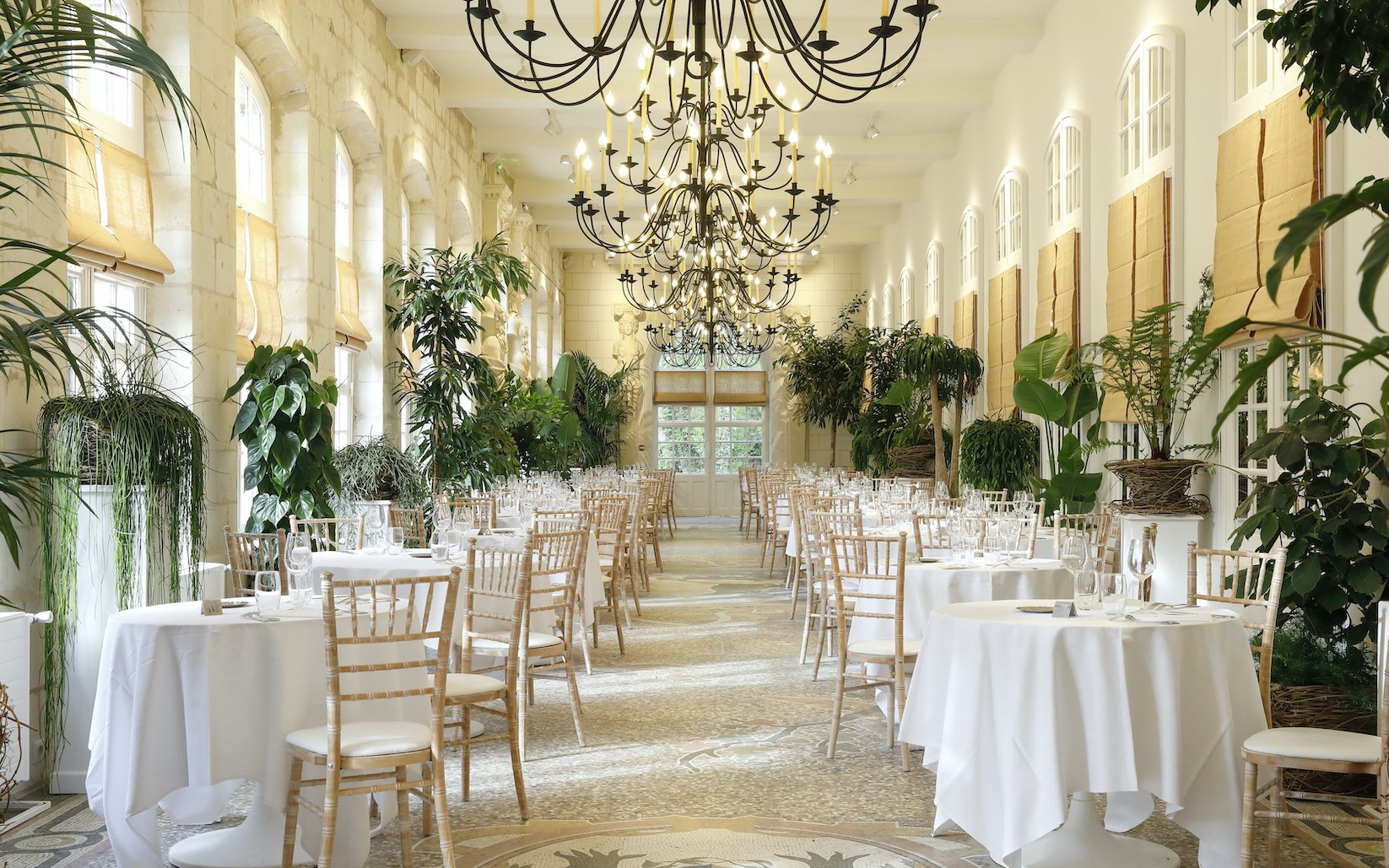 Elegant dining room with chandeliers and greenery at Chenonceau Castle, France.