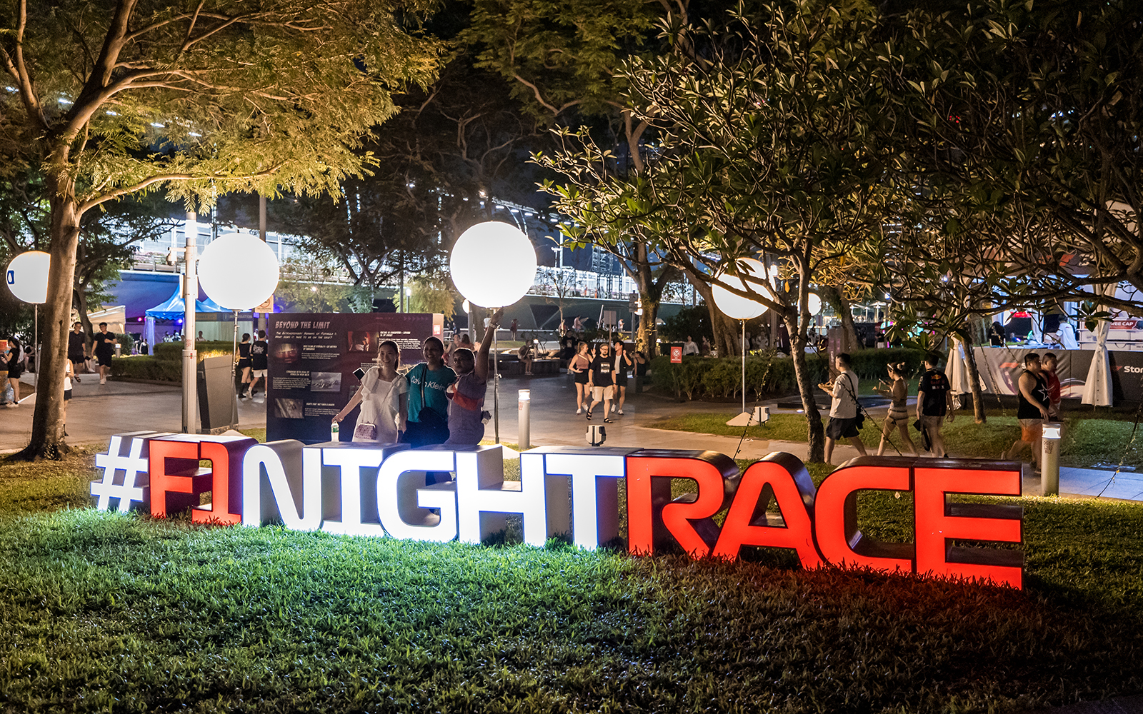 Women posing at an F1 Singapore sign.