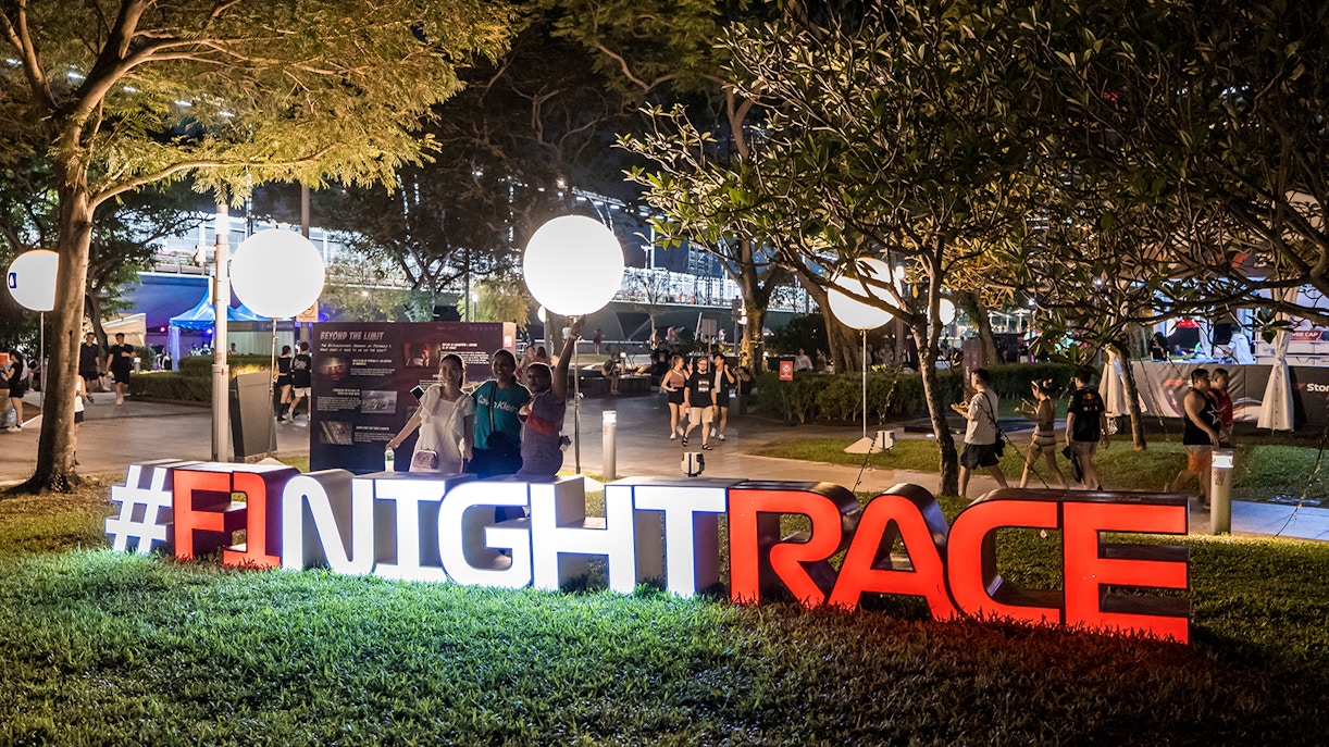 Women posing at an F1 Singapore sign.