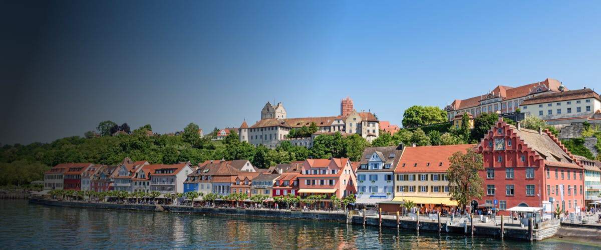 Colorful buildings along the waterfront in Rust, Germany, with a historic castle in the background.