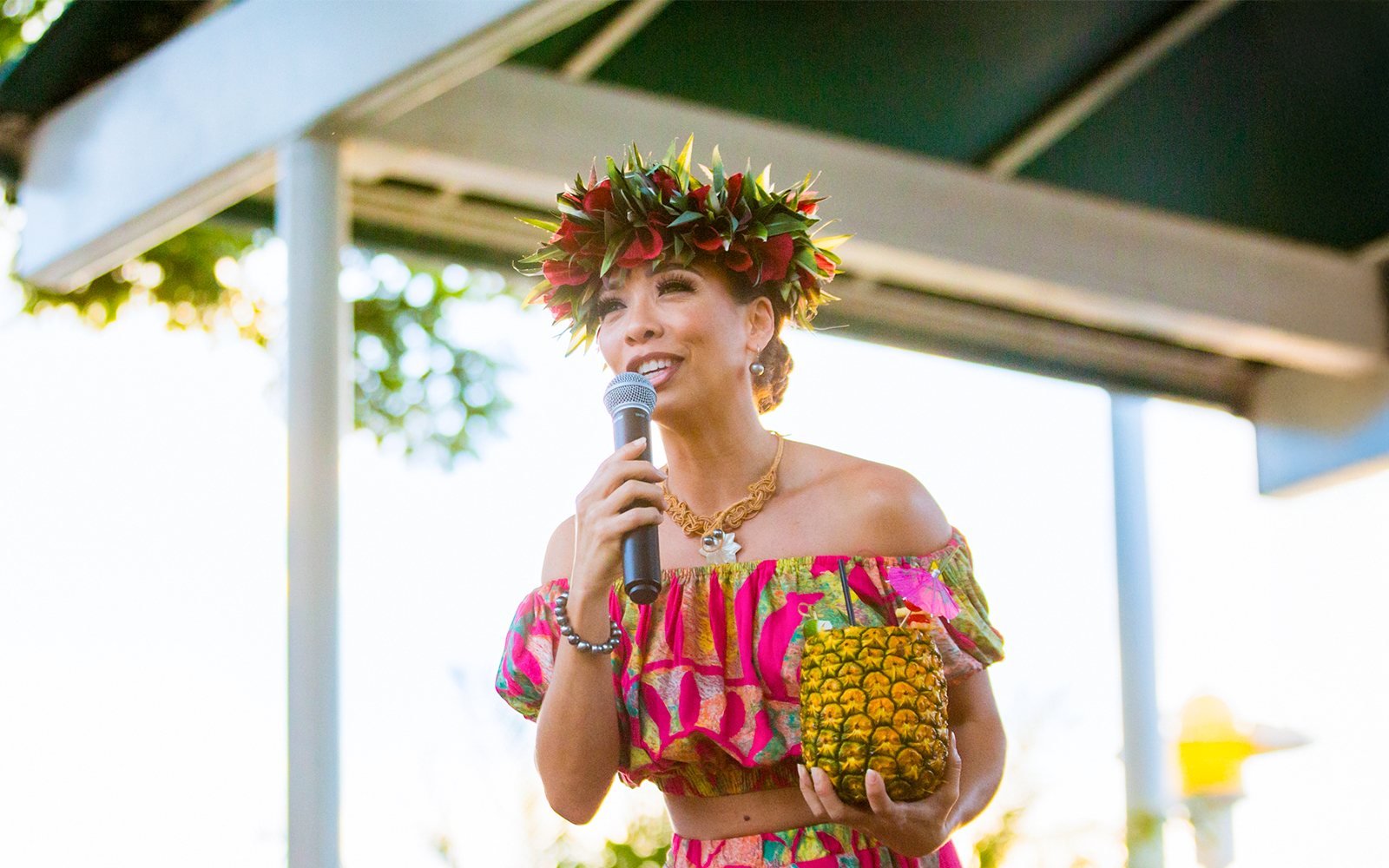Performer at Moana Luau in Hawaii holding a pineapple drink.