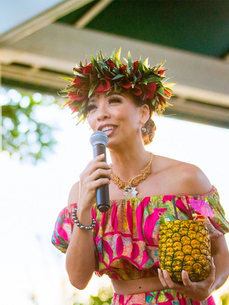 Performer at Moana Luau in Hawaii holding a pineapple drink.