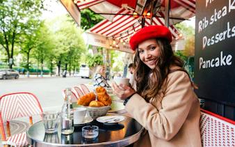 Young woman enjoying coffee at a Parisian café with croissants on the table.