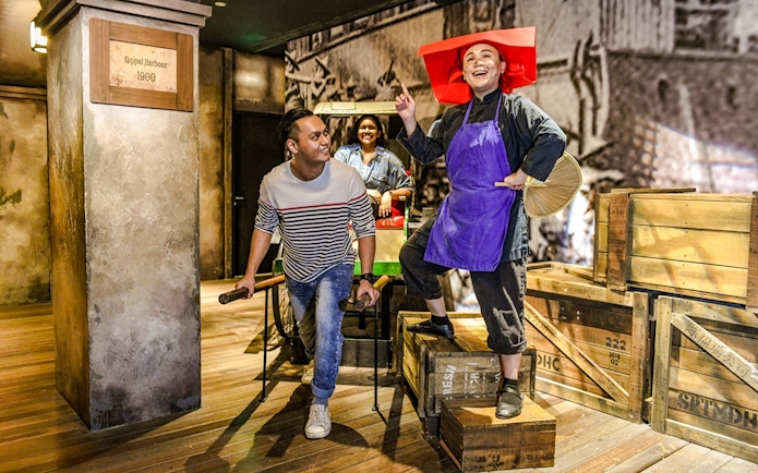 Man pulling a rickshaw with passengers at Madame Tussauds Singapore, depicting early 1900s Keppel Harbour.