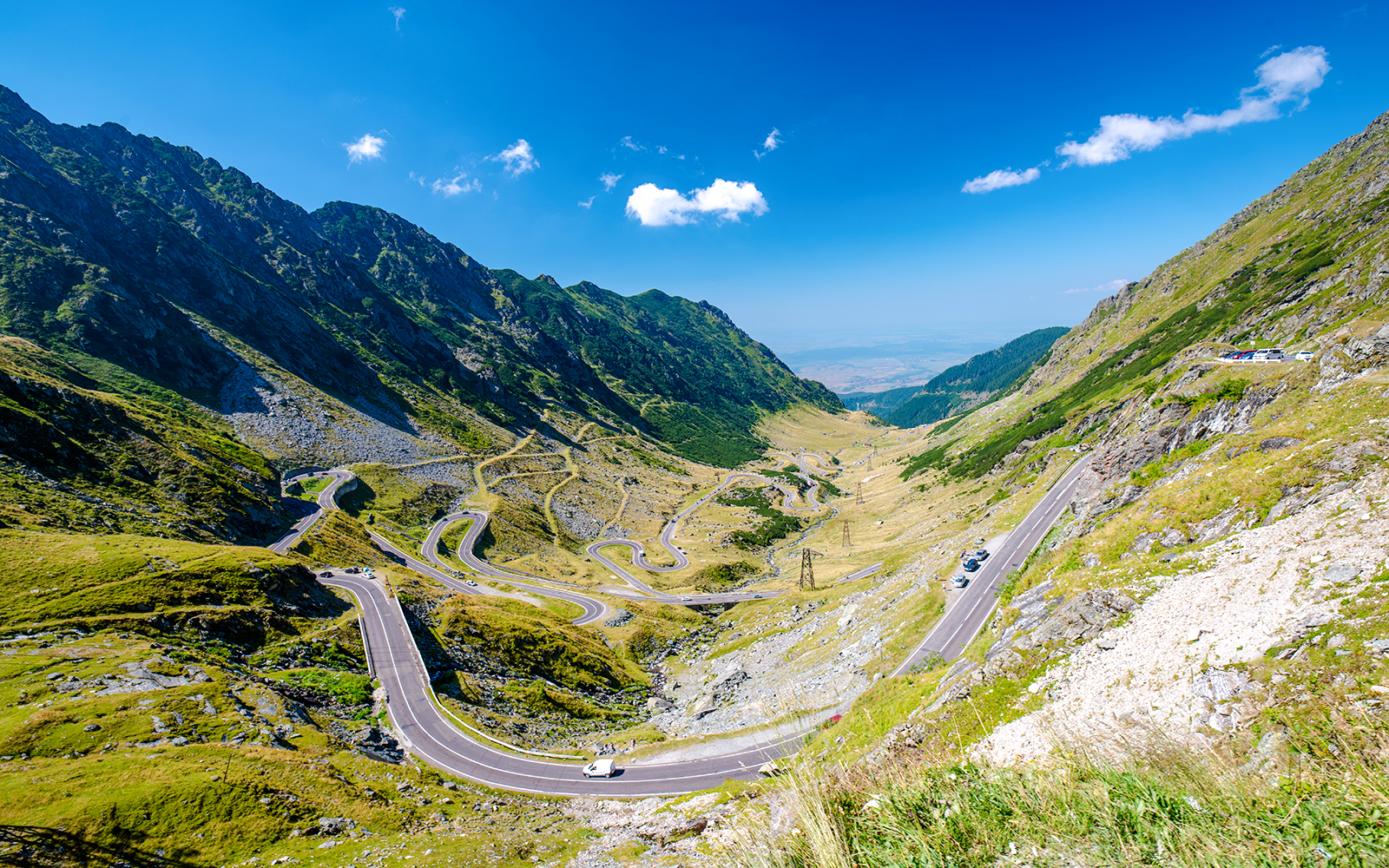 Winding Transfagarasan mountain road in Romania with cars and scenic valley view.