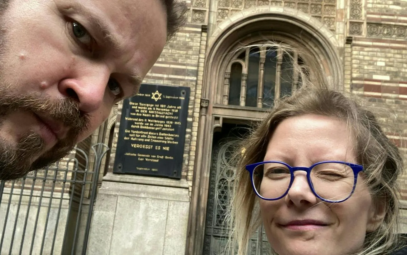 Visitors in front of a historical synagogue plaque in Berlin's Jewish District.