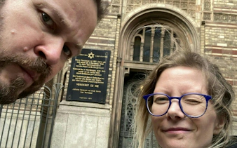 Visitors in front of a historical synagogue plaque in Berlin's Jewish District.